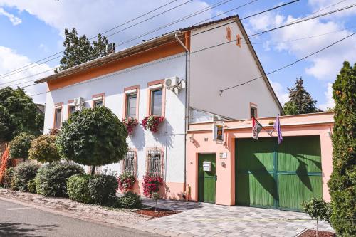 a pink and white house with a green garage at Szivárvány Panzió in Szeged