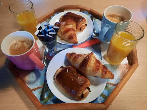 uma bandeja de café da manhã com croissants e suco de laranja em La Palmeraie em Istres
