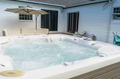 a hot tub in a backyard with an umbrella at Casa Hermes in Hamptons in Westhampton Beach