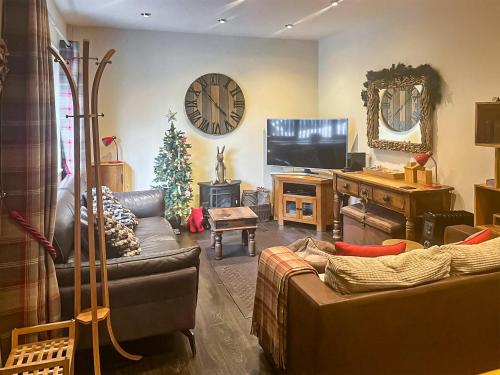 a living room with a couch and a television and a christmas tree at Ringinglow Toy Cottage in Fulwood