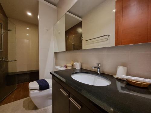 a bathroom with a sink and a toilet and a mirror at Peter Pan Poolvilla in Jomtien Beach