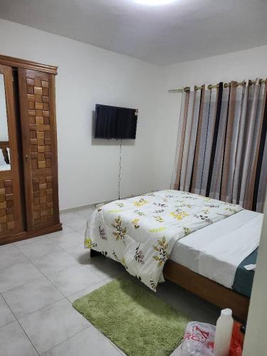 - une chambre avec un lit et une télévision murale dans l'établissement JADO House, à Dakar