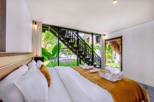 una camera da letto con un grande letto con una grande finestra di Seaside Hermitage Cosy Bungalow Near Canggu Beach a Canggu