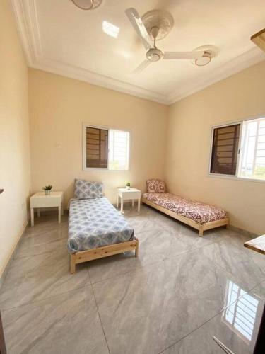 Habitación grande con 2 camas y 2 mesas. en KMR Apartment - Sira, en Sere Kunda