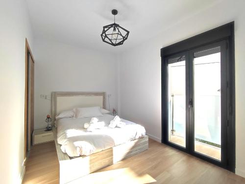 a bedroom with a bed with white sheets and a window at Ohana homes 3 in Málaga