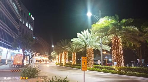 a street with palm trees decorated with lights at night at Mactan Newtown Beach Condo in Mactan