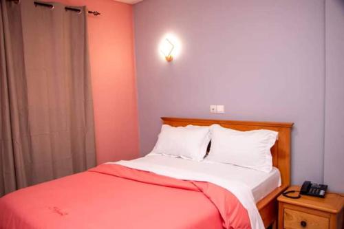 una camera con letto rosso e bianco e comodino di Résidence l'Appart a Yaoundé