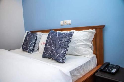 un letto con due cuscini e un telecomando di Résidence l'Appart a Yaoundé