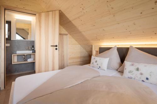 a large bed in a room with a wooden ceiling at Streuobst Chalets in Neukirch