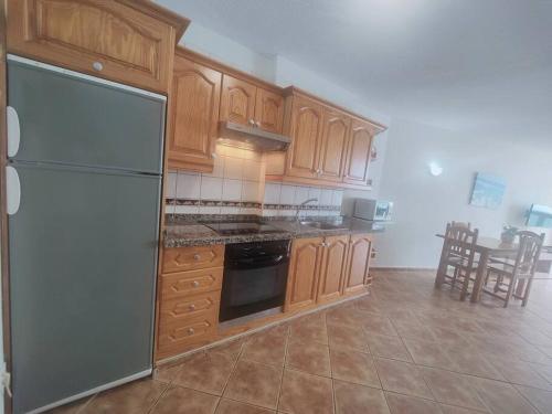 - une cuisine avec des placards en bois et un réfrigérateur dans l'établissement Atardecer con vistas al Teide, à Tacoronte