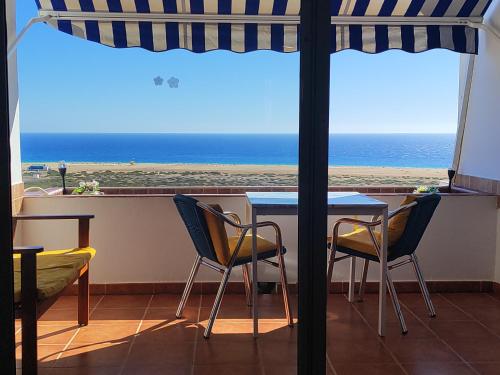 een tafel en stoelen met uitzicht op het strand bij apartamentos Vv casafaromar in Morro del Jable