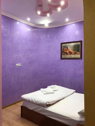 a purple wall with a bed in a room at Hrashq Hotel in Yerevan