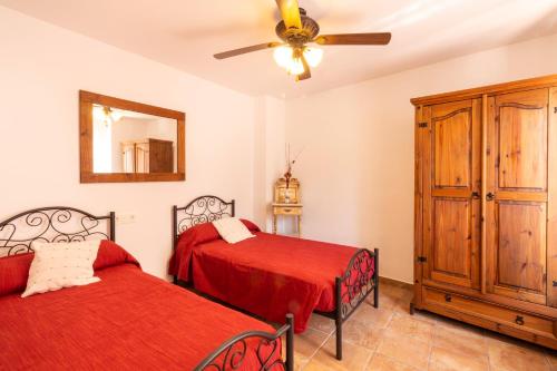 a bedroom with two beds and a ceiling fan at Casa Generalife, bei Granada in Dúrcal