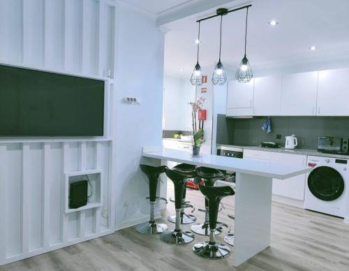 a kitchen with a white counter and green stools at Santo António Guest Apartment in Funchal