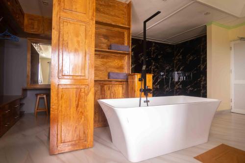 uma banheira num quarto com uma porta de madeira em Azamat Self-Catering Apartment em Mahé