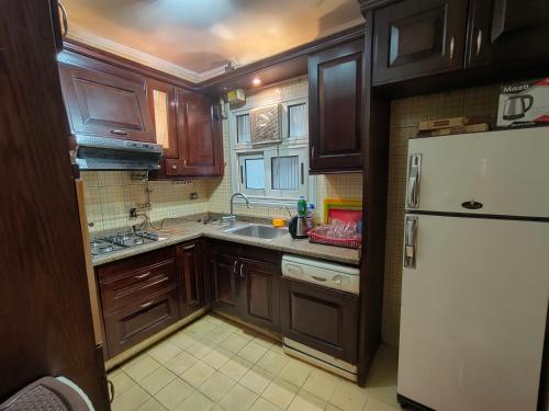 a kitchen with wooden cabinets and a white refrigerator at شقه مفروشه مميزه جدا لعائله بالدقي in Cairo