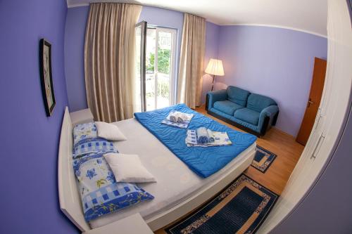 a small bedroom with a bed and a blue chair at Lidia Apartments in Budva