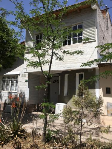 Una casa blanca con un árbol delante. en Habitación doble en Luján de Cuyo