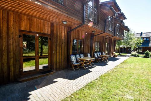 a wooden building with chairs and a table on a patio at Vila Ambasada in Šventoji