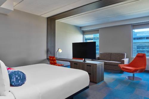 a hotel room with a bed and a flat screen tv at Aloft Richardson in Richardson
