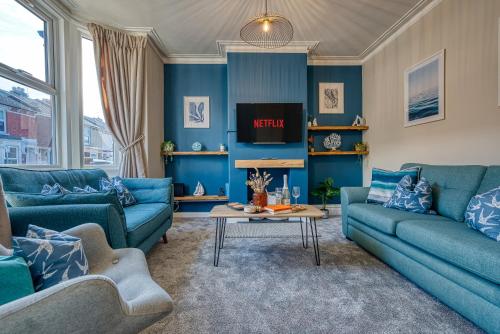 a blue living room with blue couches and a table at 2-Bedroom Modern, Stunning & Stylish Contractor House, Sleeps 4, Prime Portsmouth Location with Free Parking Permit - by Blue Puffin Stays in Portsmouth