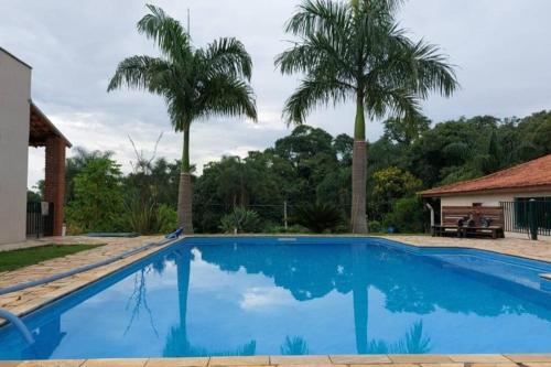 una piscina azul con dos palmeras en el fondo en Casa de Hóspede Canto do Canto, en Itapetininga