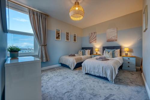 a bedroom with two beds and a window at 2-Bedroom Modern, Stunning & Stylish Contractor House, Sleeps 4, Prime Portsmouth Location with Free Parking Permit - by Blue Puffin Stays in Portsmouth