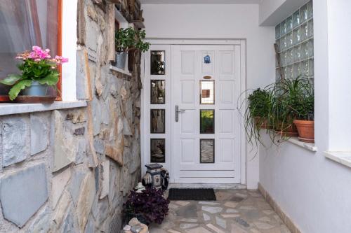 une porte blanche avec des plantes sur un mur en pierre dans l'établissement The Blue House, à Sečovlje