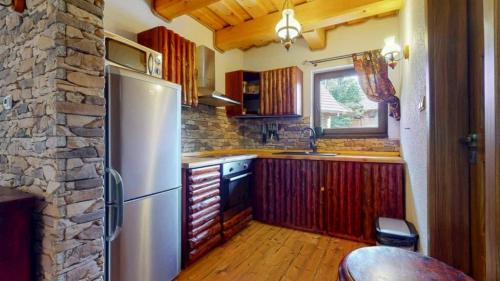 a kitchen with a refrigerator and a stone wall at Chata Mlynná in Mýto pod Ďumbierom