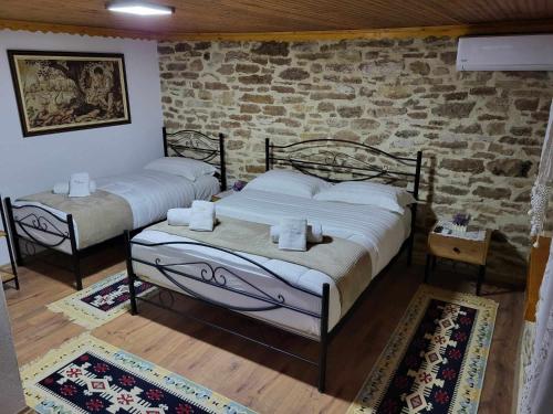 two beds in a room with a brick wall at Guest House Hasko in Gjirokastër