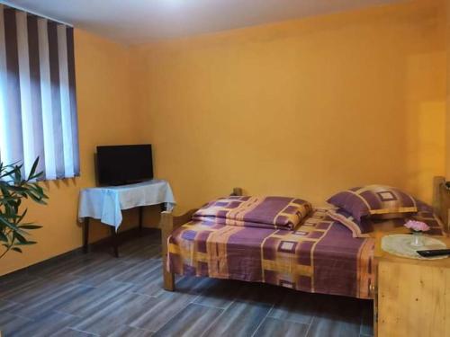 a bedroom with a bed and a table and a television at Pensiunea Trei brazi Scărișoara in Scărişoara