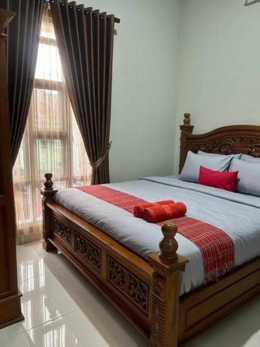 een slaapkamer met een bed met rode kussens en een raam bij AW Kinanti Homestay in Timuran
