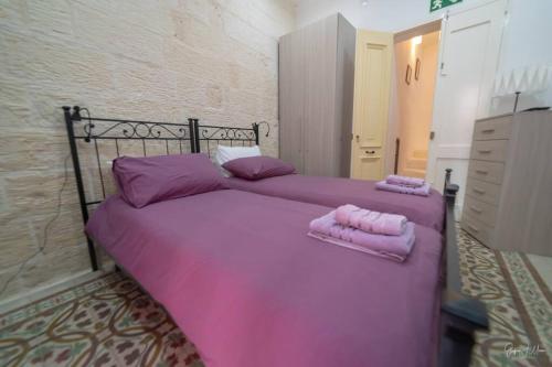 1 dormitorio con 2 almohadas rosas en una cama en Quaint Studio apartment, en Birgu