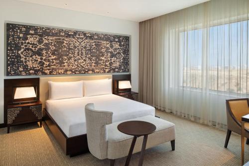a bedroom with a bed and a chair and a window at JW Marriott Hotel Muscat in Muscat