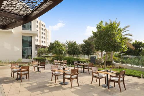 a patio with tables and chairs in front of a building at JW Marriott Hotel Muscat in Muscat