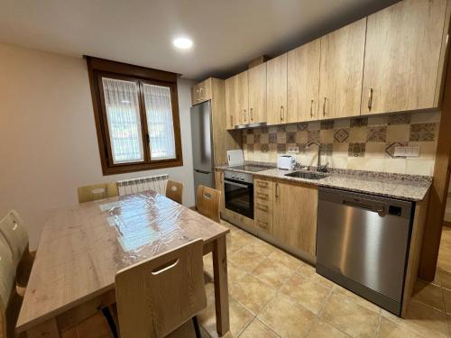 a kitchen with a table and a stainless steel refrigerator at Apartamentos La Flor in San Martín de Moncayo