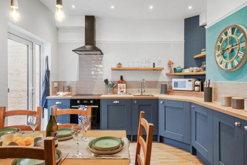 una cocina con armarios azules y una mesa con sillas en 3 - Bed Spacious Luxury Townhouse, Great for Contractors & Groups l Sleeps 6 with Free Parking - Blue Puffin Stays, en Portsmouth