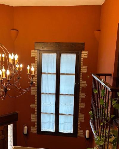 a window in an orange room with a chandelier at La Flor del Granado in Torrijos