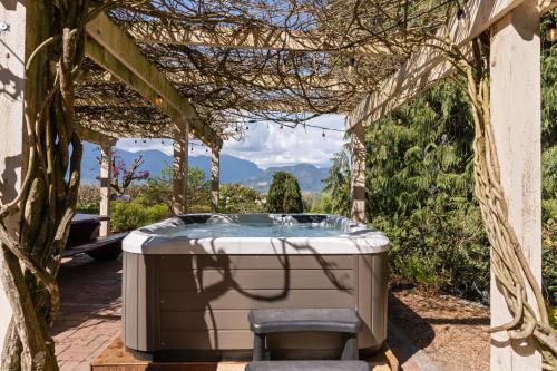 a hot tub in a pergola with a chair at Grand English Style Home in Chilliwack