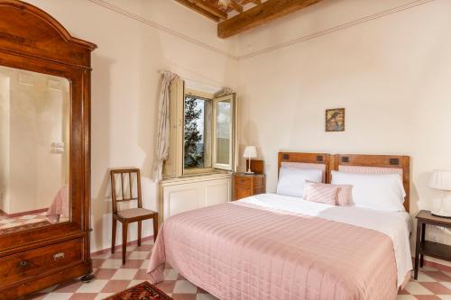 een slaapkamer met een bed, een stoel en een raam bij Il Vescovo, Incredible Attic in center of Montepulciano, Luxe in Montepulciano