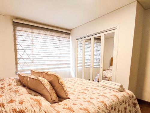 a bedroom with a bed with pillows and a window at Precioso apartamento cerca del Aeropuerto de Bogta in Bogotá
