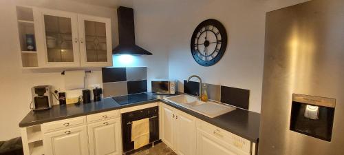 une cuisine avec une horloge murale et un évier dans l'établissement La maison de vos vacances, à Marmeaux