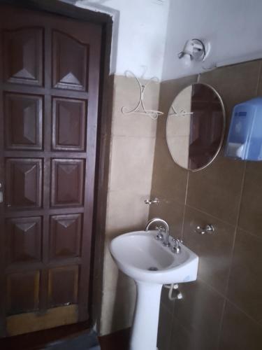 a bathroom with a sink and a mirror and a door at Trinidad Hostal in San Salvador de Jujuy