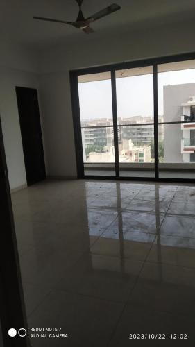 Habitación vacía con ventilador de techo y ventana grande. en Shubh Antilia, en Ahmedabad