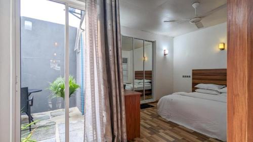 een slaapkamer met een bed en een groot raam bij Coco Villa Ukulhas in Ukulhas