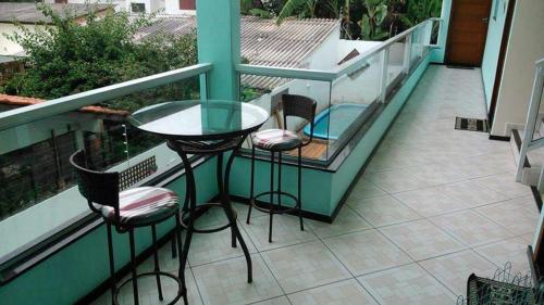 a balcony with a table and chairs and a swimming pool at Residencial Vovó Luiz in Florianópolis