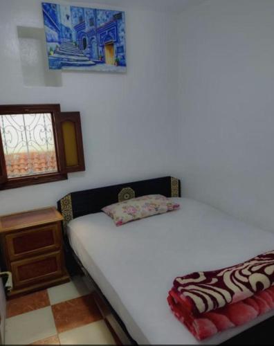 1 dormitorio con cama blanca y ventana en Blue Medina Chefchaouen, en Chefchaouen