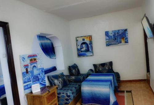 sala de estar con sofá azul y pinturas en la pared en Blue Medina Chefchaouen, en Chefchaouen