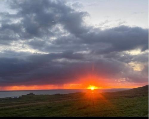 una puesta de sol en un campo con la puesta de sol en Sea View B & B, en Ulsta