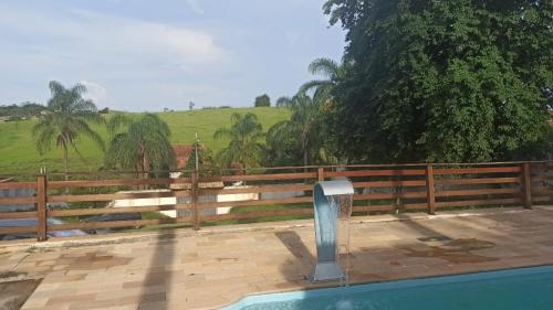 uma piscina com cerca e árvores ao fundo em Chácara Refúgio da Carol em Taubaté